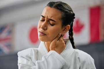 Canvas Print - Woman karate student with bad neck pain at fitness training studio, person holding head from sport injury at health gym and muscle cramp from learning self defense at school. Painful joint accident