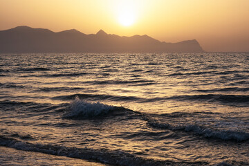  Sunset on island of Sicily, Italy.Waves against the background of the setting sun. Silhouette of mountains in background. Relax, evening on vacation.
