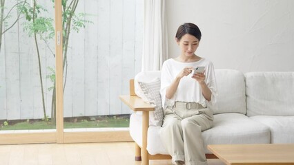 Leinwandbilder - 笑顔でスマホを見るミドル女性