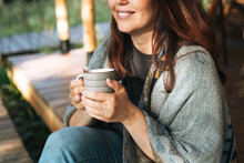 Young Brunette Woman In Poncho Drinking Tea And Relaxing In Glamping In Nature