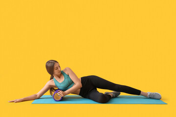 Canvas Print - Young woman training with purple foam roller on yellow background