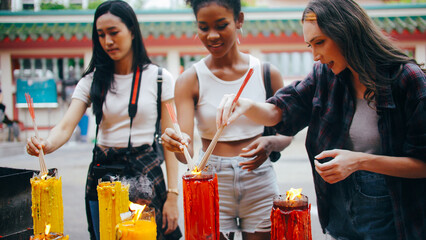 A group of multi-ethnic female friends praying at a Chinese shrine in Bangkok, Thailand.