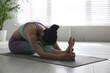 © New Africa - Woman practicing head to knee forward bend asana in yoga studio. Janu sirsasana pose