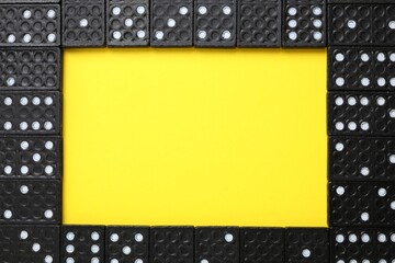 Wall Mural - Frame of black domino tiles on yellow background, flat lay. Space for text