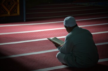 An unknown person is reading the Koran with solemnity in a mosque.