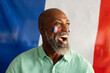Happy senior african american man sitting with flag of france and football