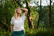 © brillianata - Beautiful young blonde in the forest. The girl enjoys nature on a summer sunny day against the background of green trees. Woman looking up at the sky