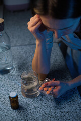 Wall Mural - An adult woman holds a package of pills. View from above. There is a glass of water next to it.