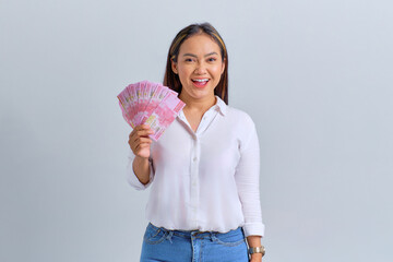 Wall Mural - Smiling young Asian woman holding money banknotes isolated over white background