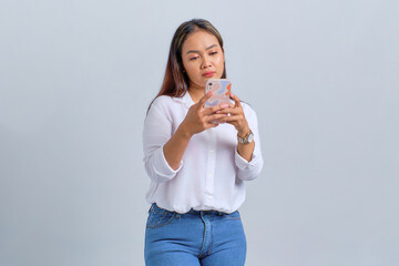 Wall Mural - Sad young Asian woman looking at mobile phone screen, reacting to bad news isolated over white background