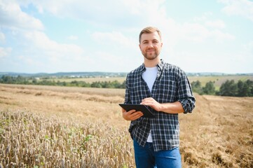 Wall Mural - Young farmer in wheat field during harvest in summer