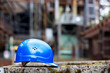 Side view of a blue safety hardhat at factory installation or construction site. Soft focus background.