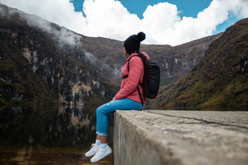 Mujer reflexionando en ella contra un lago rodeado de montañas