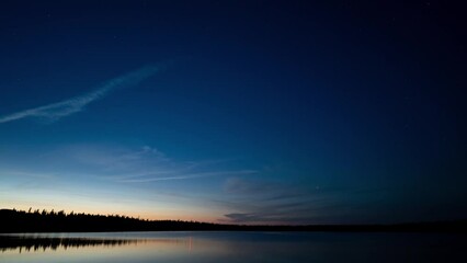 Wall Mural - time lapse of slow moving clouds and stars during blue hour above a lake with a communication tower 