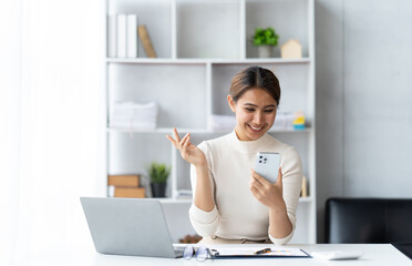 Wall Mural - Asian businesswoman in formal suit in office happy and cheerful during using smartphone and working.