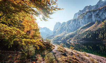 Fototapete - Wonderful autumn landscape. Popular alpine lake Grundlsee with colorful trees. Scenic image of forest landscape at sunny day. stunning nature background. Majestic Mountains on colorful scenery
