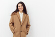 © Tatiana - beautiful, sweet, joyful woman with dark hair in a stylish beige coat. Photo on a light background