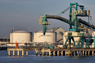 Wall Mural - Ventspils, Latvia - August 14, 2022: Big crane and large white oil fuel tanks in the port of Ventspils.