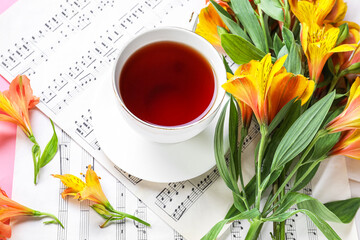 Wall Mural - Cup of tea and alstroemeria flowers on music notes, closeup