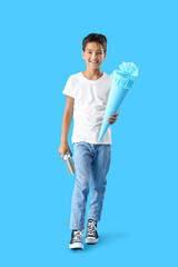 Wall Mural - Little boy with school cone and books on blue background