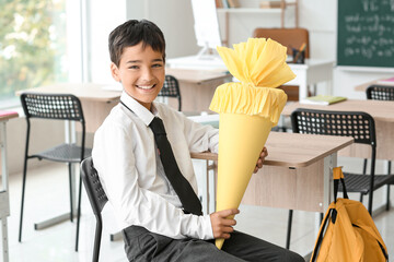 Wall Mural - Little boy with yellow school cone in classroom