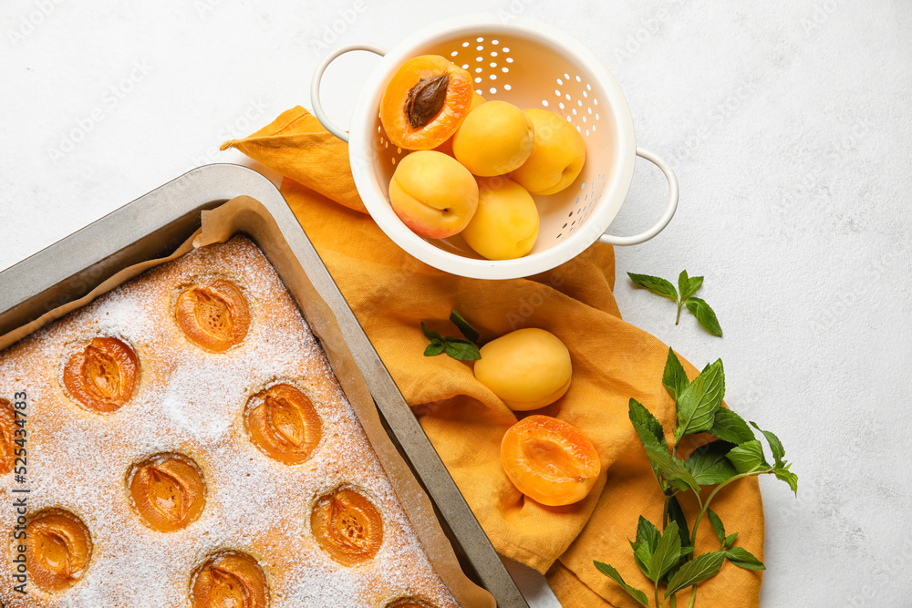 Tasty apricot pie, fruits and mint on light background