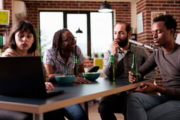 Wall Mural - Multiethnic group of friends sitting at home together while watching drama movies on laptop computer. Diverse people sitting at table in living room while enjoying leisure activity.