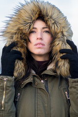 Wall Mural - Portrait of young woman in winter wearing coat with fur hoodie