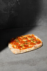 Sticker - Traditional italian food - Pizza pepperoni on dark background. Pepperoni pinsa on gray stone table with hard shadow. Roman pizza with pepperoni and jalapeno on concrete background. Pinsa menu.