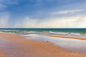 Sticker - Seascape view at a sand beach with rain in the horizon