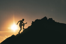 A Man Runs Among The Rocks In A Colorful Mountain Sunset
