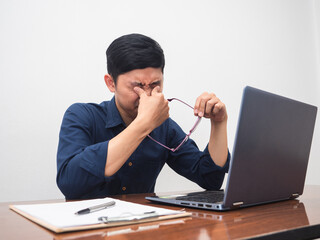 Man tried form work hard take off his glasses sit at workplace table
