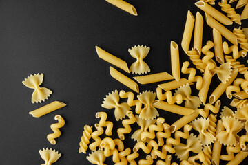 Canvas Print - Different kinds of raw pasta with copy space on black background.