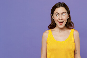 Wall Mural - Young happy fun surprised impressed woman 20s she wear yellow tank shirt look aside on workspace area mock up isolated on plain pastel light purple background studio portrait People lifestyle concept