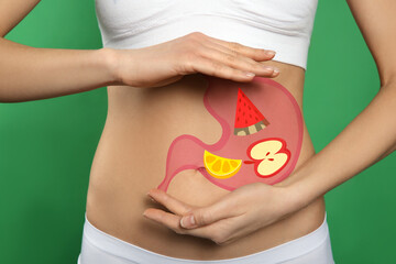 Canvas Print - Woman with image of stomach full of food drawn on her belly against green background, closeup. Healthy eating habits