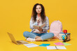 © ViDi Studio - Full body minded young black teen girl student she wearing casual clothes backpack bag hold books sitting on floor isolated on plain yellow color background. High school university college concept