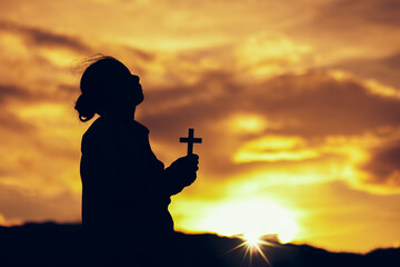Sticker - Silhouette of woman praying and worship with holding Cross in hands at sunset. worship to God. Christian Religion concept background. Copy space for your individual text.
