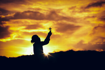 Sticker - Silhouette of a woman holding christian cross and praying worship at sunset. worship to God. Christian Religion concept background. Copy space for your individual text.