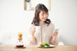 © amanaimages - 食事をしながらスマートフォンを見る女性