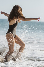 Woman Playing With Ocean Waves On A Sunny Day