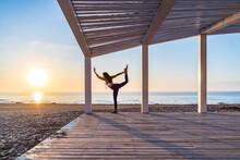 Woman Doing Yoga In Standing Split Pose At Seaside