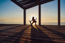 Tranquil Woman Doing Yoga In Warrior Pose During Sunrise