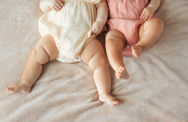 no face two active little twin baby girls lying on bed