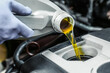 Car oil is pouring into the engine close up. pouring new oil into the engine. automobile engine oil change. vehicle maintenance concept