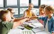 © JenkoAtaman - Teacher and joyful students celebrate   successful completion of collective school work in a bright classroom