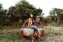 Charming Woman Sitting On Rusty Wagon In Countryside