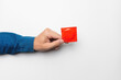 A man's hand holds a red condom in a package on a white background. High definition product. Close-up. Contraception