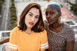 © ADDICTIVE STOCK - Multiracial lesbian couple sitting close together outdoors