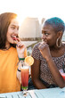 © ADDICTIVE STOCK - Multiethnic couple of cool lesbian women drinking cocktails