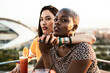 © ADDICTIVE STOCK - Multi ethnic lesbian couple relaxing with cocktails